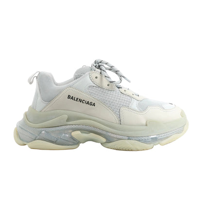 Side view of a gray Balenciaga Triple S 541624 sneaker in size 44 EU, featuring layered mesh and leather upper, thick translucent and rubber sole, and round laces with black stripes.