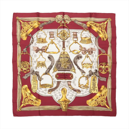 Hermès Carré 90 "Étriers" Silk Scarf in red, featuring detailed golden stirrup and equestrian motifs arranged symmetrically on a white center background, bordered with deep red edges and intricate ribbon-like accents.