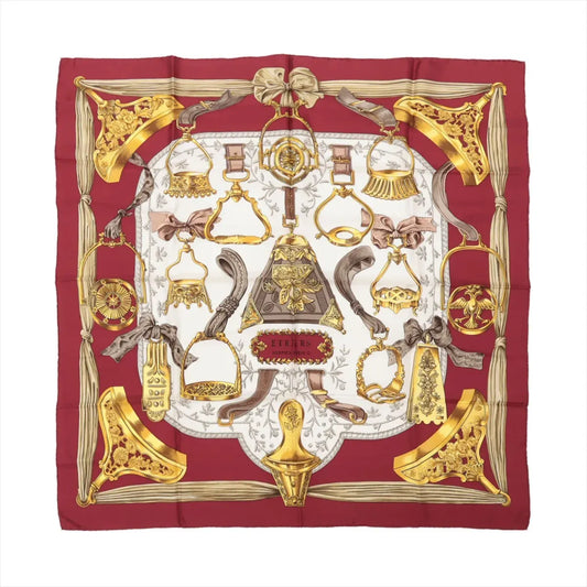 Hermès Carré 90 "Étriers" Silk Scarf in red, featuring detailed golden stirrup and equestrian motifs arranged symmetrically on a white center background, bordered with deep red edges and intricate ribbon-like accents.