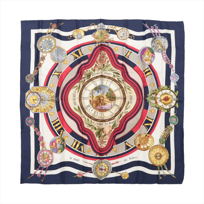 Hermès Carré 90 "Parmi les Fleurs je Compte les Heures" silk handkerchief in navy blue, showcasing a central floral-framed clock surrounded by ornate vintage-style timepieces and Roman numerals, with red, cream, and gold accents on luxurious silk fabric.