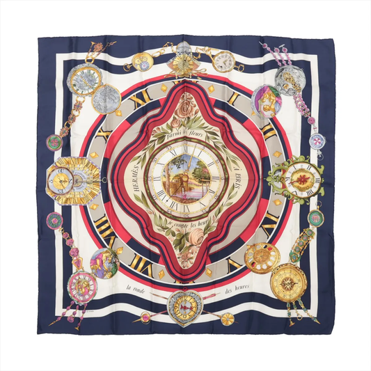 Hermès Carré 90 "Parmi les Fleurs je Compte les Heures" silk handkerchief in navy blue, showcasing a central floral-framed clock surrounded by ornate vintage-style timepieces and Roman numerals, with red, cream, and gold accents on luxurious silk fabric.