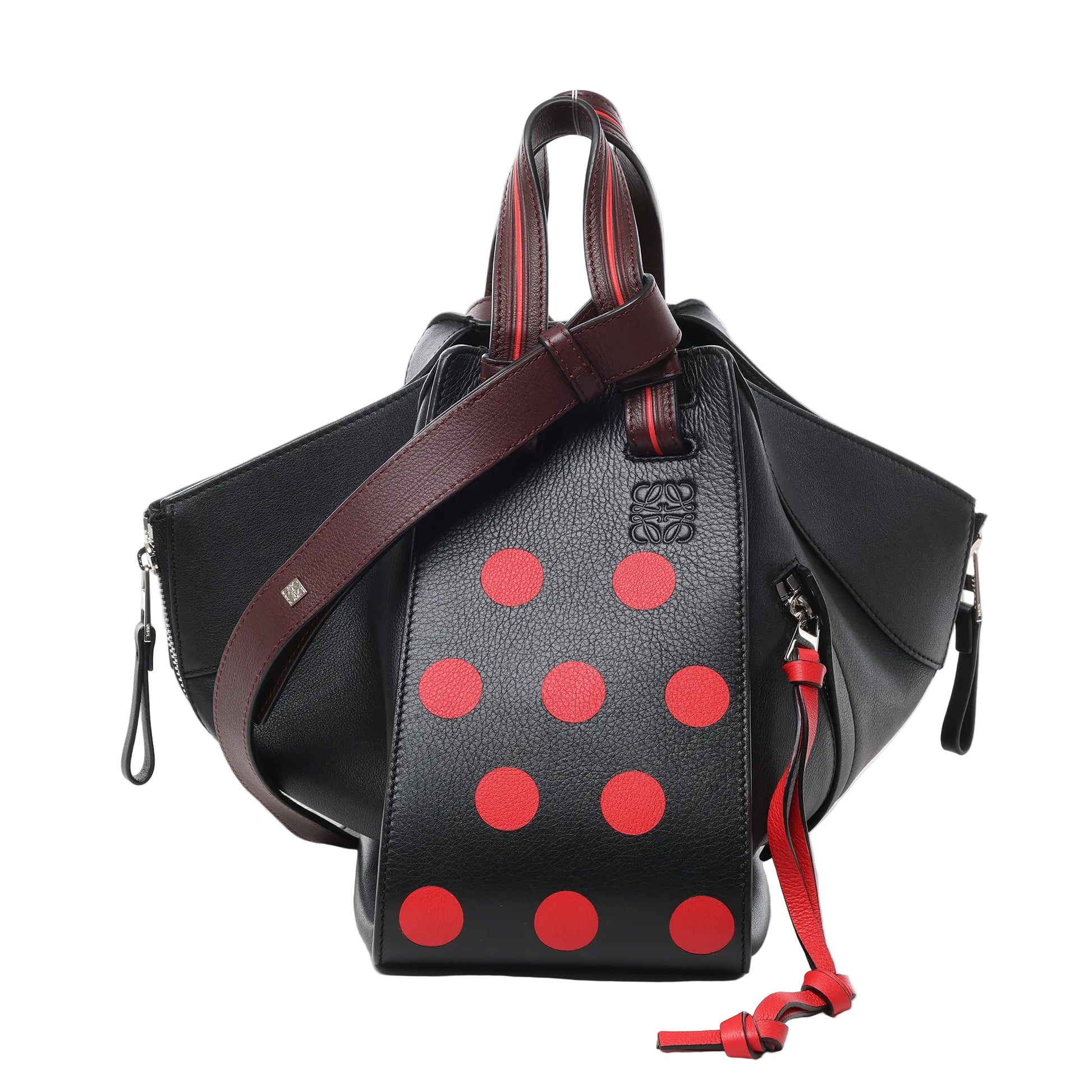Front view of LOEWE Hammock Small Leather 2Way Handbag in black with red polka dot design, featuring pebbled leather texture, burgundy leather top handles and strap, expandable side panels, and silver-tone hardware against a white background.