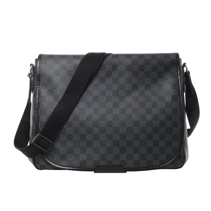 Front view of Louis Vuitton Damier Graphite Daniel MM Shoulder Bag N58029 in black checkered coated canvas, featuring flap closure, adjustable black fabric shoulder strap, and leather trim against a white background.