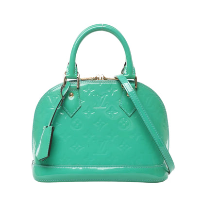 Front view of Louis Vuitton Monogram Vernis Alma BB handbag M90302 in glossy green patent leather, featuring embossed LV monogram, gold-tone hardware, dual top handles, and detachable shoulder strap against a white background.