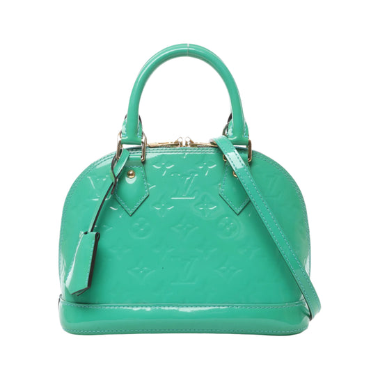 Front view of Louis Vuitton Monogram Vernis Alma BB handbag M90302 in glossy green patent leather, featuring embossed LV monogram, gold-tone hardware, dual top handles, and detachable shoulder strap against a white background.