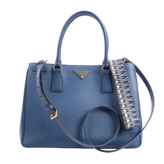 Blue handbag with decorative strap on a white background
