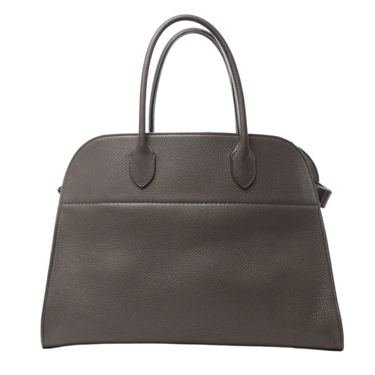 Front view of The Row Soft Margaux 15 Leather Handbag in gray grained leather with dual top handles and a structured, minimalist design, displayed against a white background.