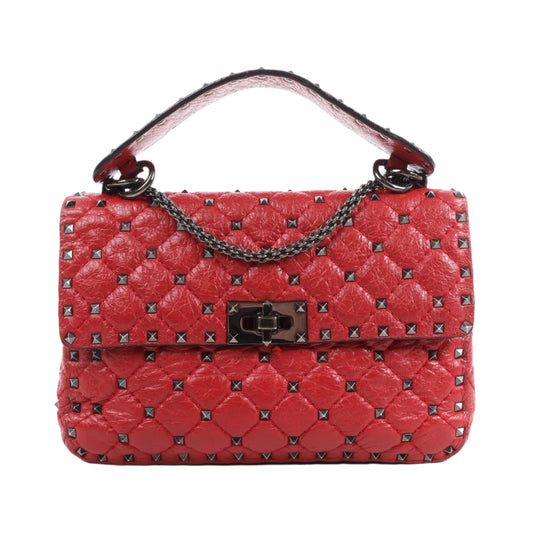 Red quilted handbag with studded details on a white background